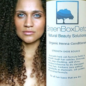 May include: A white bottle with a green label that reads "GreenBoxDetox Natural Beauty Solutions Organic Henna Conditioner Strength Shine Bounce". The label also includes a description of the product's benefits, including that it is an Ayurvedic herb rich formula that fortifies and smooths rough hair cuticles, eliminates frizz, stops shedding, adds shine, and moisturizes and bounces dry damaged hair. The label also states that the product contains zero artificial ingredients or chemicals and is enriched with silk protein. The label also states that the product is for all hair types that are dry.
