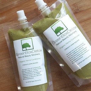 May include: Two green squeeze bottles of organic henna conditioner labeled "GreenBoxDetox Natural Beauty Solutions" with the text "Strength Shine Bounce" and a description of the product's benefits.