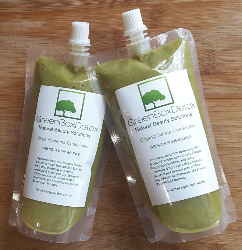 May include: Two green pouches of organic henna conditioner from GreenBoxDetox Natural Beauty Solutions. The pouches are labeled "Strength Shine Bounce" and contain an Ayurvedic herb-rich formula to fortify and smooth hair.