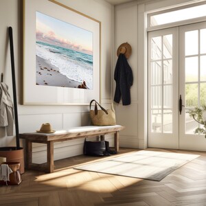 May include: A wooden bench with a white cushion sits in a hallway with a framed beach scene on the wall, a straw bag, and a hat hanging on a hook.