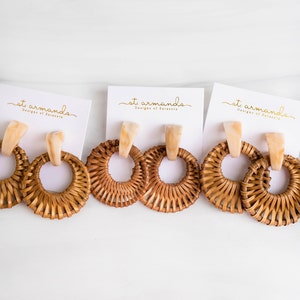 May include: Three pairs of brown woven circle earrings with white and gold accents. The earrings are displayed on white cards with the text "st. armonds Designs of Sarasota" printed on them.