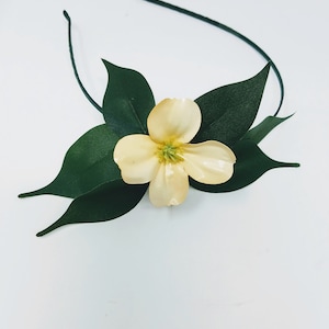 May include: A headband with a single yellow flower and green leaves.