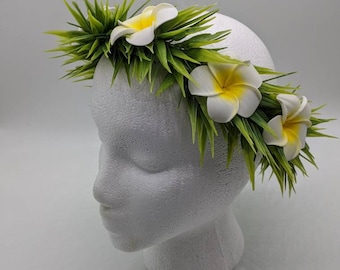 Può includere: Un lei di fiori bianco e giallo con foglie verdi. Il lei è fatto di fiori e foglie artificiali.