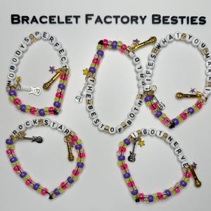 May include: Five beaded bracelets with white letter beads spelling phrases like NOBODY'S PERFECT, THE BEST OF BOTH WORLDS, LIFE'S WHAT YOU MAKE IT, ROCK STAR, and I GOT NERVE. Each bracelet features colorful pink, purple, and lime green beads and charms.