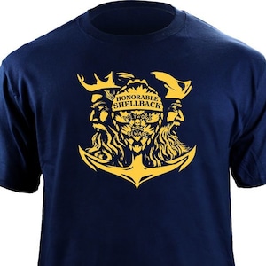 May include: A navy blue t-shirt with a yellow anchor and two bearded faces. The text "HONORABLE SHELLBACK" is above the anchor. The text "WHO'S AFRAID OF A LITTLE WATER?" is inside the anchor.