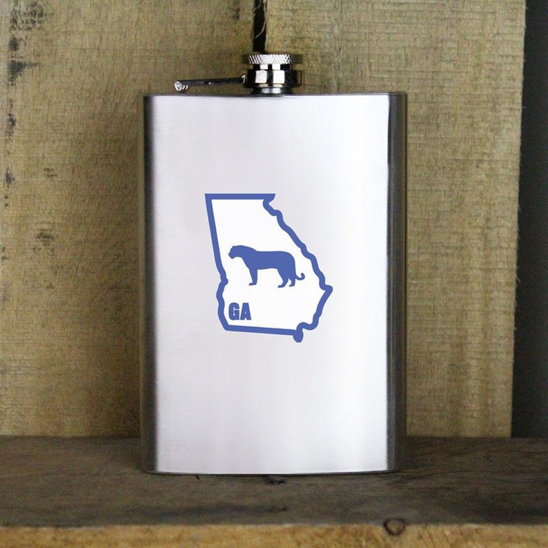 May include: A stainless steel flask with a blue outline of the state of Georgia and a blue silhouette of a panther inside the outline. The text "GA" is below the panther.