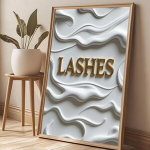 以下が含まれることがあります： 金色の文字で「LASHES」と書かれた額入りのアートプリント。背景はテクスチャ加工された白いデザイン。フレームは明るい木の色で、アートワークは壁に立てかけられています。