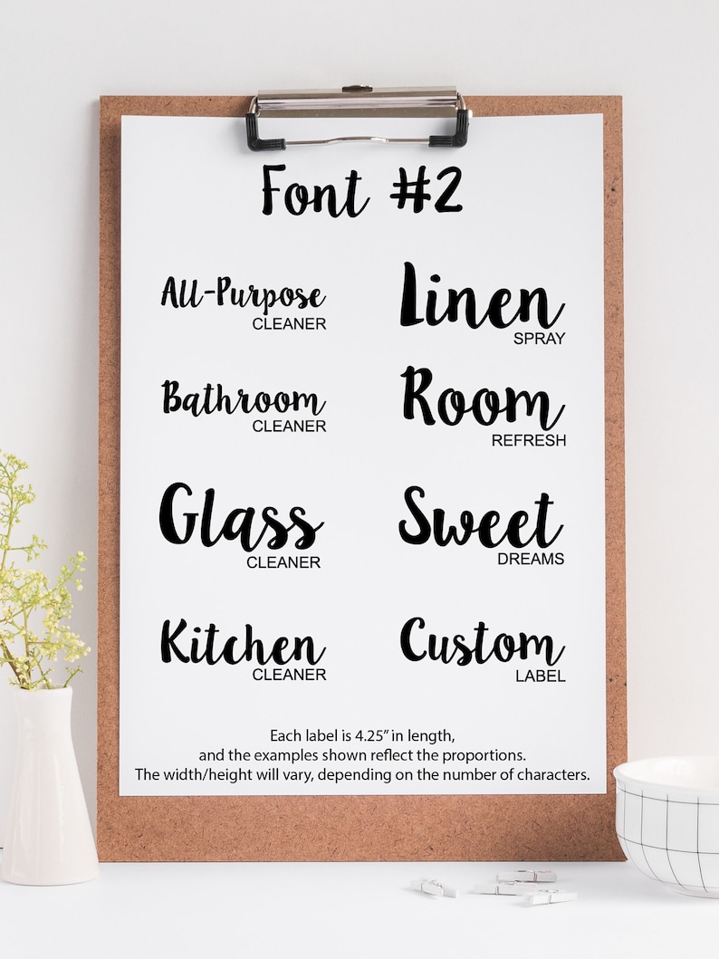 May include: A black and white image of a clipboard with a handwritten font style guide. The font is called "Font #2" and is used for labels. The labels are 4.25 inches long and include the following text: "All-Purpose Cleaner", "Linen Spray", "Bathroom Cleaner", "Room Refresh", "Glass Cleaner", "Sweet Dreams", "Kitchen Cleaner", and "Custom Label".
