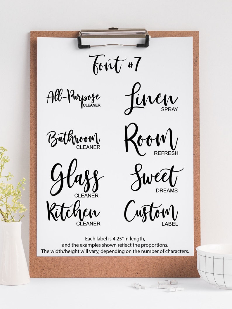 May include: A white clipboard with a black clip holds a sheet of paper with a font sample. The font is a cursive script style. The text on the sheet reads "Font #7" and includes examples of the font with different words like "All-Purpose Cleaner", "Linen Spray", "Bathroom Cleaner", "Room Refresh", "Glass Cleaner", "Sweet Dreams", "Kitchen Cleaner", and "Custom Label". Each label is 4.25 inches in length.