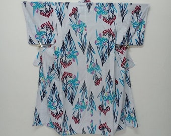Puede incluir: Yukata de algodón blanco con un estampado floral azul, rosa y rojo. El estampado presenta flores de iris estilizadas con hojas.
