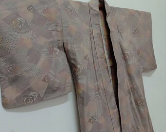 Puede incluir: Un kimono japonés marrón y beige con un patrón geométrico de cuadrados y círculos. El kimono tiene un diseño floral con acentos rosas y amarillos.