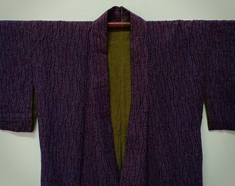 Puede incluir: Un kimono japonés morado y verde con un patrón ondulado. El kimono está hecho de una tela suave y ligera y tiene un diseño tradicional.