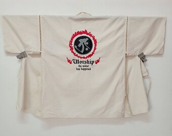 May include: A white kimono with a red and black circle graphic on the back. The graphic includes the text "Worship the worst has happened".