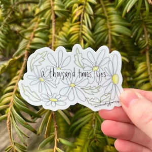 Puede incluir: Una pegatina blanca con un diseño floral con margaritas y hojas. La pegatina tiene el texto "a thousand times. yes" y la firma "sincerely frances".