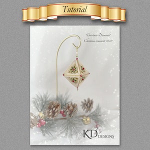 以下が含まれることがあります： 赤いアクセントが付いたダイヤモンド型の白と金のビーズでできたクリスマスオーナメント。オーナメントは、キラキラとした効果のある白い背景に、金のスタンドから吊り下げられています。画像には「Christmas Diamonds」と「Christmas ornament 2022」のテキストが表示されています。