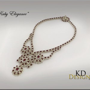 Peut inclure: Un collier de perles argent&eacute;es et rouges avec un motif floral. Le collier s'appelle "Ruby Elegance".