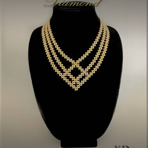May include: A gold beaded necklace with a diamond-shaped design. The necklace is on a black display stand. The text "Diamond" is above the necklace.