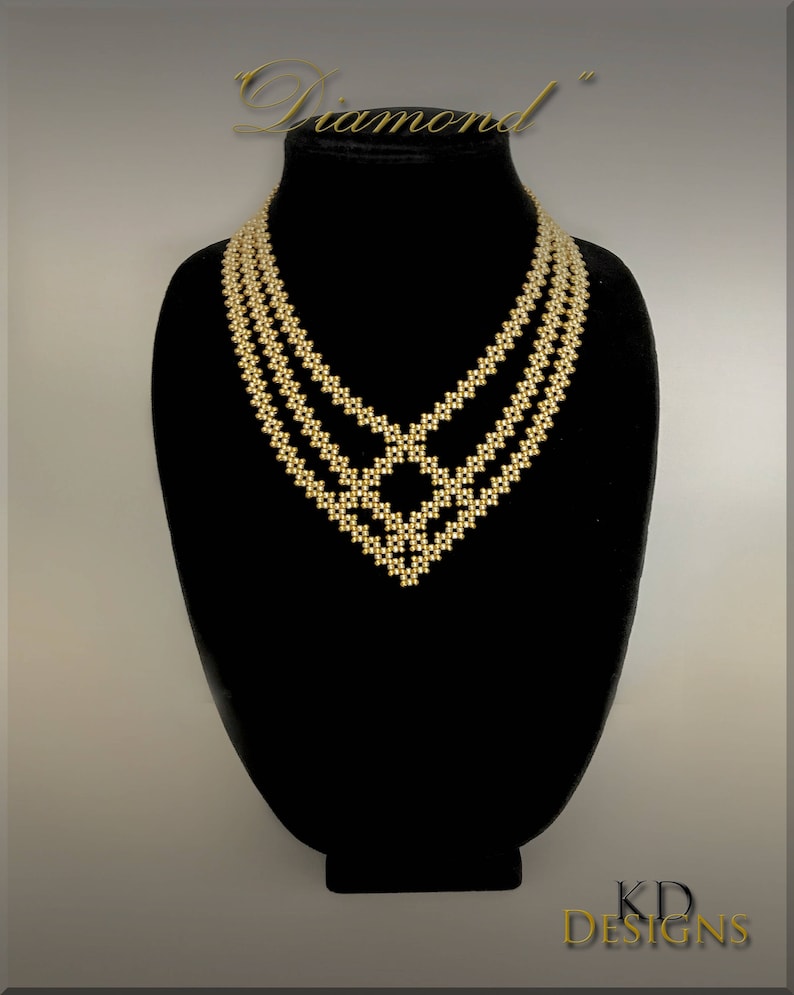 May include: A gold beaded necklace with a diamond-shaped design. The necklace is on a black display stand. The text "Diamond" is above the necklace.