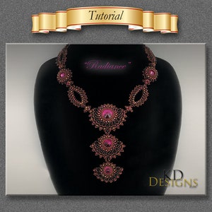 May include: A beaded necklace with a pink and brown color scheme. The necklace features a large, central pendant with a pink stone and smaller, surrounding stones. The necklace is labeled "Radiance" and "KD Designs".