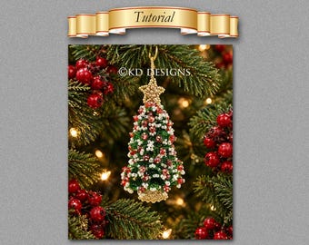May include: A beaded Christmas tree ornament featuring a gold star topper, green, red, and white beads, and the text KD DESIGNS. The ornament hangs from a gold loop against a background of evergreen branches with red berries and warm lights.