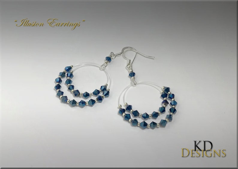 May include: A pair of silver hoop earrings with a double row of dark blue crystal beads. The earrings are labeled "Illusion Earrings".