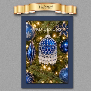 May include: A blue and silver beaded Christmas ornament hanging on a pine tree with warm lights. The ornament features intricate beadwork and dangling crystals. The text OKD DESIGNS is visible above the ornament, and a banner labelled Tutorial is at the top.