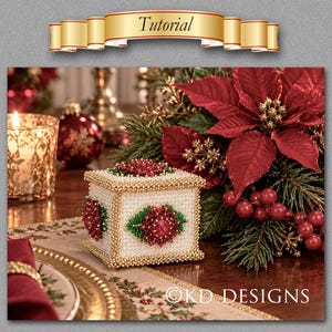 May include: A square box covered in white beads with gold beaded edges, featuring a central red and green beaded poinsettia motif on the side and top. The text "Tutorial" appears in a gold banner above, and "KD DESIGNS" is printed at the bottom.