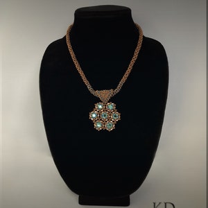 May include: A copper and turquoise beaded necklace with a large pendant featuring a flower design with turquoise stones. The necklace is displayed on a black stand. The text "KD DESIGNS &copy;2019" is visible in the bottom right corner of the image.