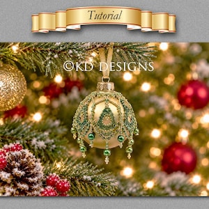 May include: A gold Christmas ornament featuring an intricate overlay of green seed beads and small green pearls. The ornament hangs from a gold ribbon and is marked with the text KD DESIGNS. The design includes delicate beadwork patterns.