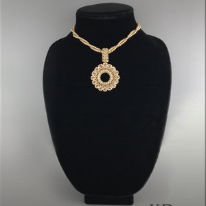 May include: A gold beaded necklace with a large, circular pendant. The pendant is made of small, gold beads arranged in a circular pattern.