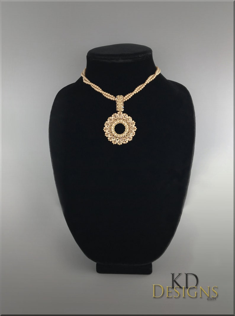 May include: A gold beaded necklace with a large, circular pendant. The pendant is made of small, gold beads arranged in a circular pattern.