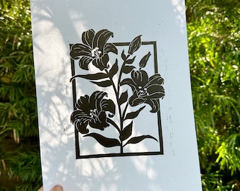 Może przedstawiać: Czarno-biały wydruk trzech lilii w kwadratowej ramie. Lilie są stylizowane i mają prosty, graficzny design.