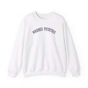 Könnte beinhalten: Weißer Langarm-Pullover mit einem dunkelblauen gestickten Bogen mit der Aufschrift "MASHED POTATOES".