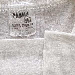 May include: White tag with black text that reads "PROMO BIZ Promo Biz Designs Inc. TORONTO ONTARIO (415) 492-1774 ONE SIZE/UNE GRANDEUR"