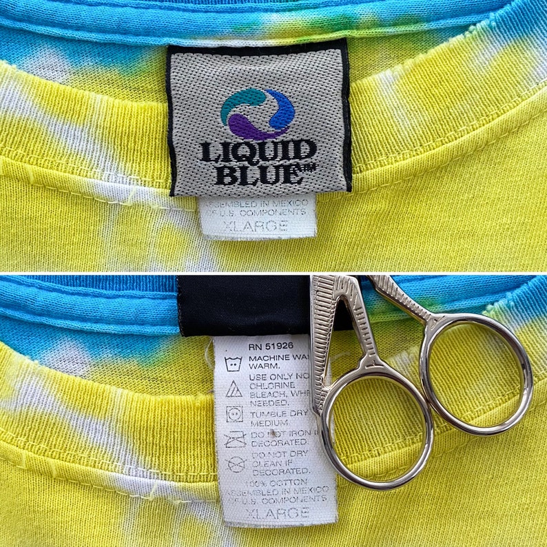 Op de afbeelding: Een geel, blauw en wit tie-dye T-shirt met een Liquid Blue-label. Het label zegt "Assembled in Mexico of U.S. Components" en "XLARGE".