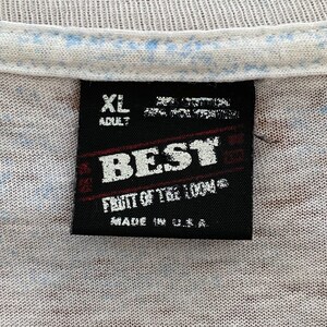 Puede incluir: Primer plano de una etiqueta de camiseta. La etiqueta negra presenta la palabra "BEST" en letras blancas, con "FIGHT OF THE 1994" debajo. La etiqueta tambi&eacute;n dice "MADE IN U.S.A." y "XL ADULT".