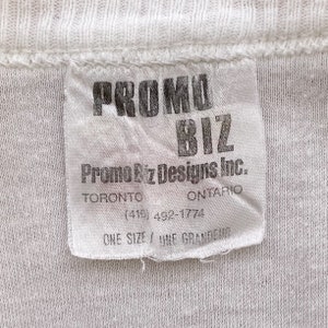 May include: White tag with black text that reads "PROMO BIZ Promo Biz Designs Inc. TORONTO ONTARIO (416) 492-1774 ONE SIZE / UNE GRANDEUR"
