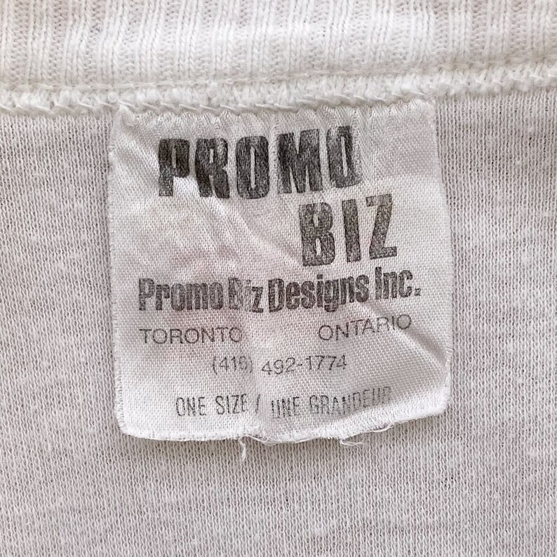 May include: White tag with black text that reads "PROMO BIZ Promo Biz Designs Inc. TORONTO ONTARIO (416) 492-1774 ONE SIZE / UNE GRANDEUR"
