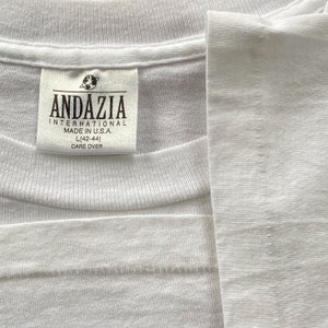 May include: White t-shirt with a white tag that reads "Andazzia International Made in U.S.A. L(42-44) Care Over"
