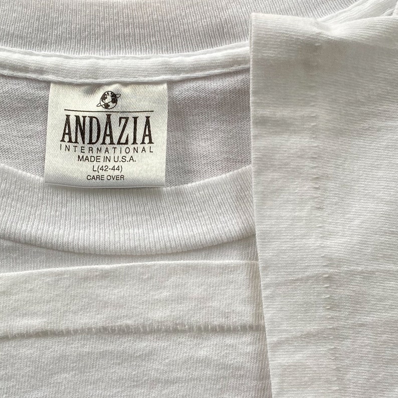 May include: White t-shirt with a white tag that reads "Andazzia International Made in U.S.A. L(42-44) Care Over"