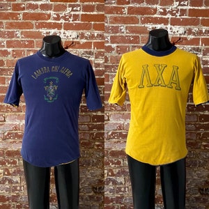 May include: Two vintage t-shirts, one navy blue with the text "Lambda Chi Alpha" and a crest, and one yellow with the text "LΧA" in navy blue.