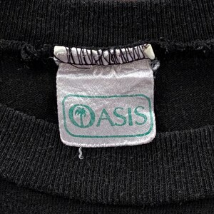 May include: A white tag with a green border and the word "Oasis" in black text. A palm tree icon is to the left of the word "Oasis".