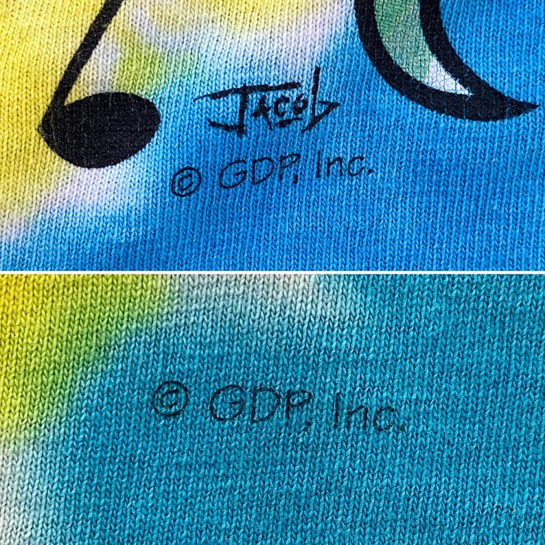 Op de afbeelding: Een close-up van een blauwe en groene tie-dye stof met de tekst "Jacob &copy; GDP, Inc." gedrukt in zwart.