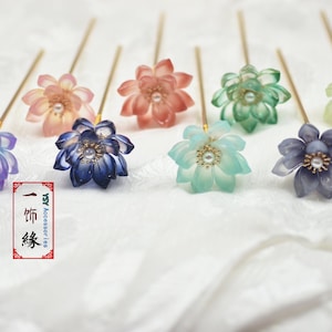 May include: Eight gold hair pins with different colored flower-shaped tops. The flowers are made of translucent plastic and have a pearl in the center. The flowers are in the colors purple, blue, pink, green, and light blue.