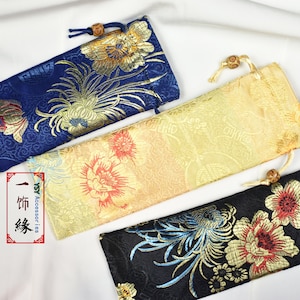 May include: Three fabric pouches with floral patterns. The pouches are blue, gold, and black with gold accents. The pouches are made of a soft, silky fabric and have a drawstring closure.