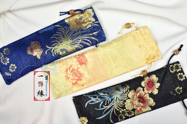 May include: Three fabric pouches with floral patterns. The pouches are blue, gold, and black with gold accents. The pouches are made of a soft, silky fabric and have a drawstring closure.