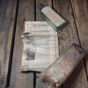 May include: An antique still life featuring a glass bottle of "Jamaica Ginger" and a torn newspaper with the headline "The Cuticura Re". The items rest on a weathered wooden surface, evoking a vintage aesthetic.