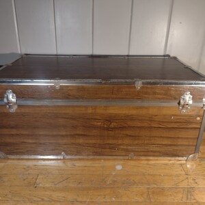 May include: A brown wooden storage trunk with silver metal accents and clasps.