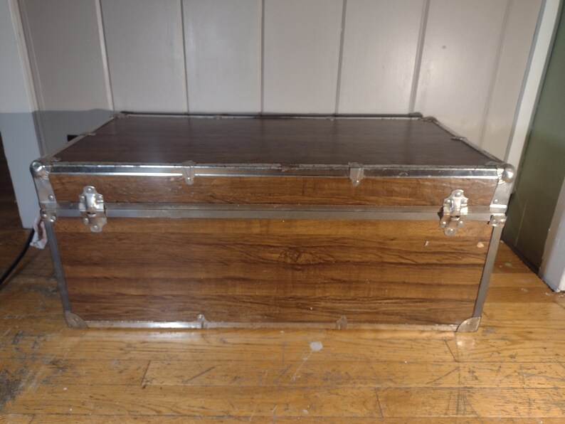 May include: A brown wooden storage trunk with silver metal accents and clasps.