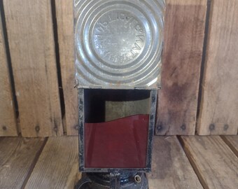 May include: A vintage metal lantern with a red glass lens and a circular metal top with the text "SIGNAL LAMP" embossed on it.